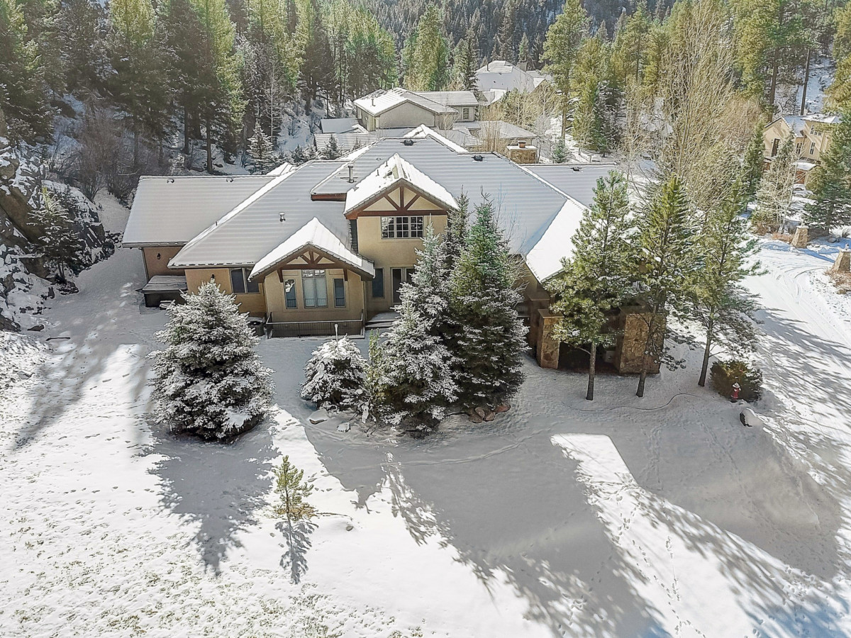 grande maison sur une propriété avec de la neige dans la cour avant et des arbres couverts de neige après une tempête hivernale