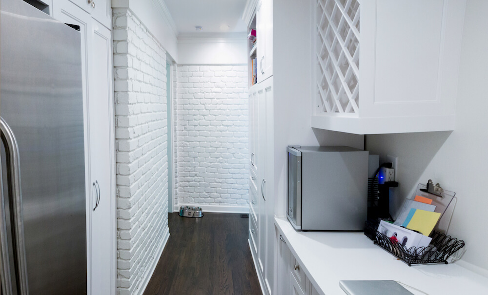 Le couloir arrière avec armoires blanches et réfrigérateur supplémentaire